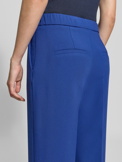 Frauenmodel trägt Weite Hose aus Viskose-Mix von s.Oliver BLACK LABEL in kräftigem Blau, glatte Struktur, Nahaufnahme Rückenansicht.