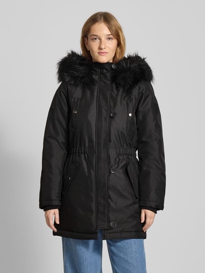 Vrouwenmodel draagt zwarte Shaped Fit Parka met Label Patch model 'IRIS' van Only, uni kleur, knopen, capuchon met imitatiebont, zakken, ribboorden, regular fit. Volledig lichaamsaanzicht van voren.