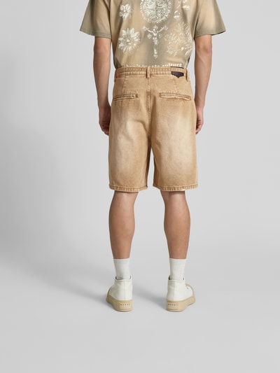 Männermodel trägt Relaxed Fit Jeansshorts aus Baumwolle von Don't Waste Culture, Used-Look, Gürtel mit D-Ring-Verschluss, Eingriff- und Gesäßtaschen, sandfarben, Ganzkörperansicht Rückansicht.