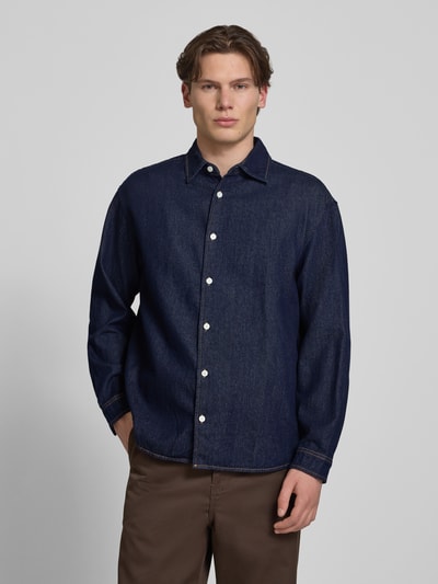 Männermodel trägt Regular Fit Jeanshemd mit Kentkragen Modell 'NORREBRO' von Jack & Jones aus reiner Baumwolle, Ganzkörperansicht von vorne.