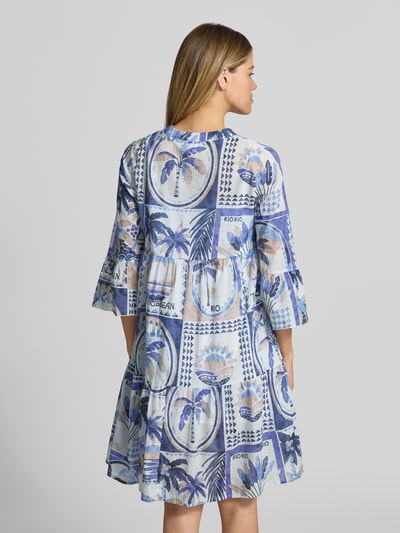 Frauenmodel trägt Tunikakleid im Allover-Look mit V-Ausschnitt von Emily Van den Bergh in Blau-Weiß, A-Linie, Rückansicht Ganzkörperansicht.