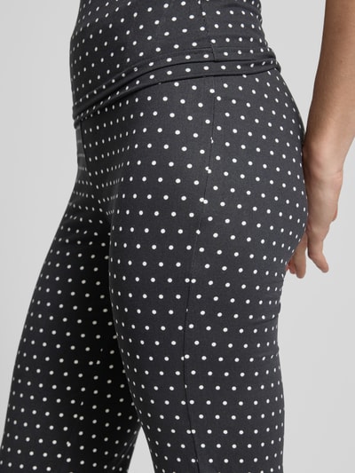 Frauenmodel trägt Flared Cut Hose im Allover-Look Modell 'DESTINY' von Noisy May aus schwarzem Material-Mix mit Stretch-Anteil und weißen Punkten, elastischer Bund mit Umschlag, Nahaufnahme Oberkörper.