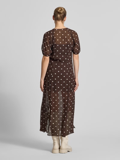 Frauenmodel trägt Regular Fit Maxikleid mit Rüschenbesatz von BAUM & PFERDGARTEN, braun mit weißen Punkten, semitransparent, Ganzkörperansicht Rückansicht.