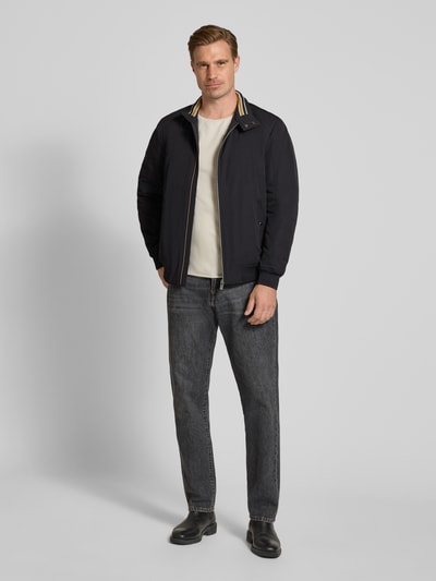 Männermodel trägt Regular Fit Jacke mit Stehkragen von Christian Berg Men in dunklem Blau, strukturierte Oberfläche, Ganzkörperansicht von vorne. Herren Jacke mit Eingrifftaschen, Reißverschluss, elastischen Abschlüssen, Rückenlänge 69 cm, Schulterbreite 49 cm, Brustweite 55 cm, Ärmellänge 67 cm.