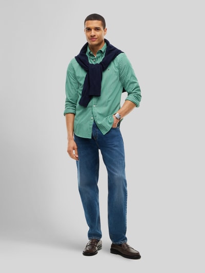 Männermodel trägt Body Fit Freizeithemd aus reiner Baumwolle von Tommy Hilfiger in Grün mit Streifenmuster, Ganzkörperansicht von vorne.