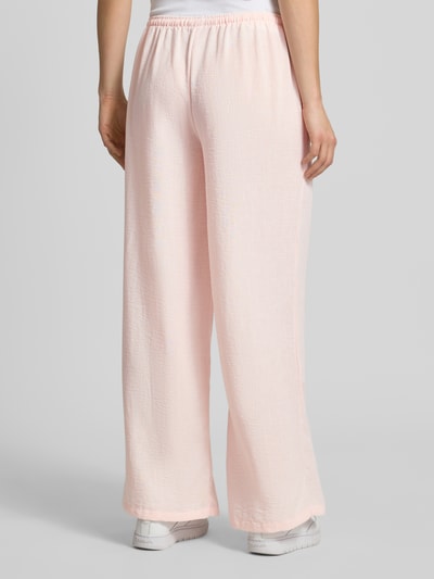 Frauenmodel trägt Pyjama Pants mit elastischem Bund von Review in zartem Rosa, Loose-Fit, Strukturtextur, Ganzkörperansicht Rückansicht, Bundweite bei Größe S 41 cm, Innenbeinlänge 77 cm.