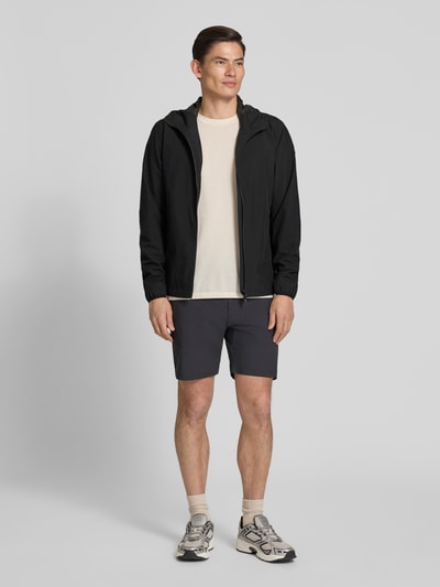 Männermodel trägt Regular Fit Jacke mit Kapuze von SCANDINAVIAN EDITION in Schwarz, Zweiwege-Reißverschluss, Eingrifftaschen, Ganzkörperansicht von vorne.