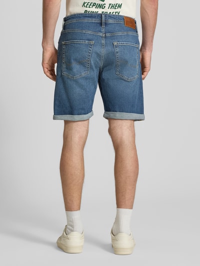Männermodel trägt Regular Fit Jeansshorts mit Umschlag Modell 'RICK' von Jack & Jones aus Baumwoll-Elasthan-Mix, Eingrifftaschen, Rückansicht Ganzkörperansicht. Bundweite bei Größe M: 42 cm, Innenbeinlänge bei Größe M: 21 cm.