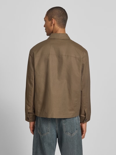 Męski model nosi Regular Fit Hemdjacke aus Leinen-Baumwoll-Mix Modell 'LEWIS' od SELECTED HOMME w jednolitym brązie, flammgarn, krój regular fit, kołnierz koszulowy, długie rękawy z mankietami na guzik, kieszenie z patkami, detal z logo, widok całej sylwetki z tyłu.