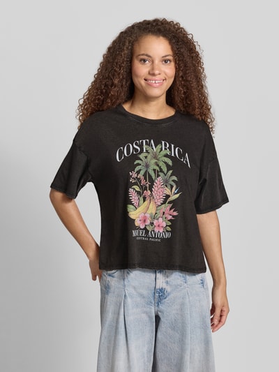 Frauenmodel trägt Damen T-Shirt von Only, Modell 'Boxy Fit T-Shirt aus reiner Baumwolle Modell LUCY', Optik: Unifarben, Boxy-Fit, Motiv-Print vorn, Rundhals, Kurzarm, Material: reine Baumwolle, florale Textur, sanfte Farben auf schwarzem Stoff, Ganzkörperansicht von vorne.