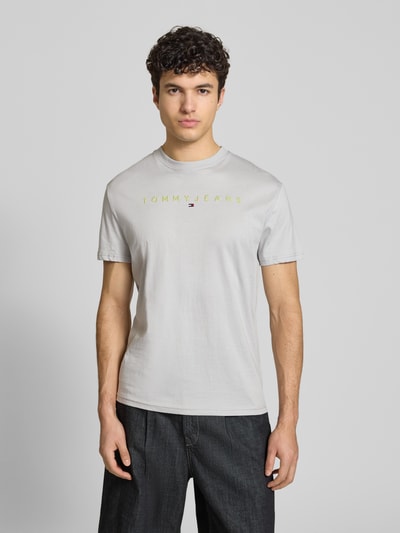 Männermodel trägt Regular Fit T-Shirt aus reiner Baumwolle von Tommy Jeans in Unifarbe mit Label Stitching, Jerseystruktur, Ganzkörperansicht von vorne.
