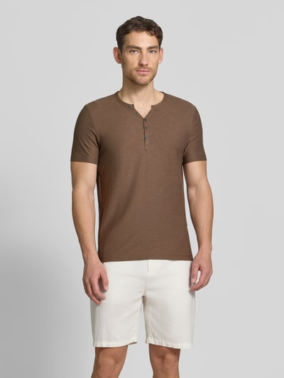 Męski model nosi T-Shirt mit V-Ausschnitt und Knopfleiste von MCNEAL, czysta bawełna, krój regular fit, długość tyłu w rozmiarze M: 68 cm, widok całej sylwetki z przodu.