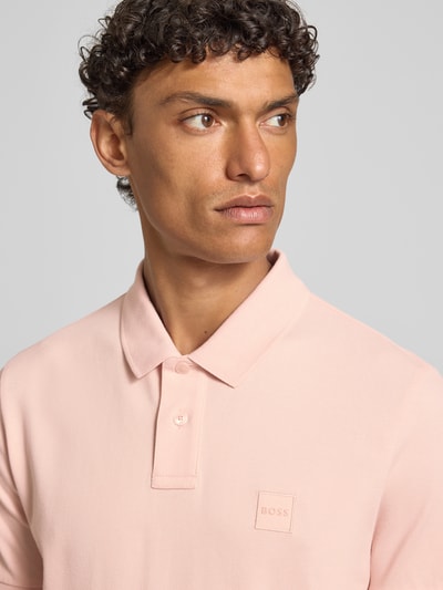 Męski model nosi Regular Fit Poloshirt aus Baumwoll-Mix Modell 'PASSENGER' od BOSS Orange, efekt: jednolity kolor, krój regular fit, wyhaftowane logo, kołnierzyk polo, dekolt w serek, krótkie zapięcie na guziki, krótki rękaw, prążkowane wykończenie rękawów, wykończenie materiału: pika, mieszanka bawełny; zbliżenie na górną część ciała z przodu.