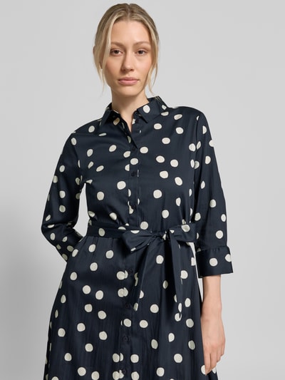 Modelka nosi Regular Fit Blusenkleid aus Baumwoll-Mix od s.Oliver BLACK LABEL, efekt: wzór w grochy na całej powierzchni, długość midi, kołnierzyk koszulowy, listwa guzikowa, pasek w talii, długi rękaw z mankietem, wpuszczane kieszenie, mieszanka bawełny. Nahaufnahme górnej części ciała.