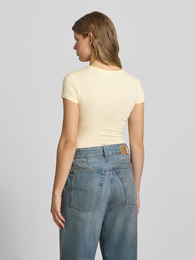 Frauenmodel trägt Slim Fit T-Shirt aus Modal-Mix von Gina Tricot in Gelb, Kurzärmelig, Rundhalsausschnitt, Rückenlänge 54 cm, Ganzkörperansicht Rückansicht.