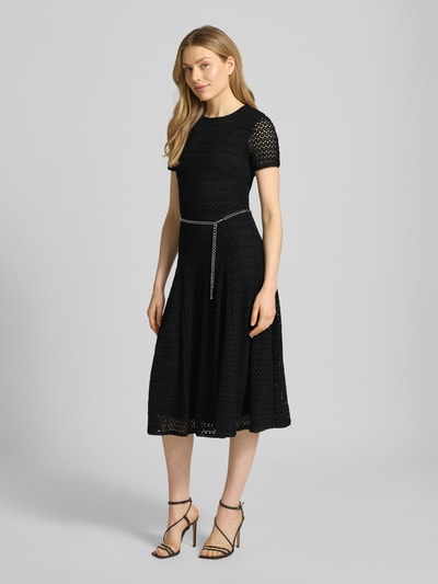 Frauenmodel trägt Midikleid mit Gürtel in Gliederketten-Optik von MICHAEL Michael Kors, Schwarz, Material-Mix mit Stretch-Anteil, taillierter Schnitt, Rundhalsausschnitt, blickdichtes Unterkleid, Ganzkörperansicht von vorne.