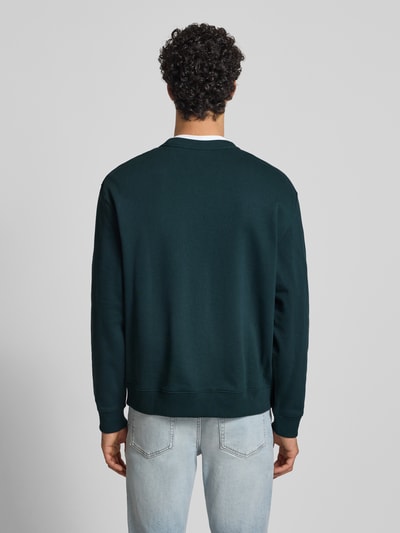 Männermodel trägt Sweatshirt aus reiner Baumwolle von Calvin Klein Jeans in Dunkelgrün mit geradem Schnitt, gerippte Abschlüsse, Rückenlänge 65 cm, Ärmellänge 63 cm, Ganzkörperansicht Rückansicht.