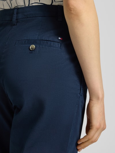 Kobiece model prezentuje Slim Fit Chino aus Baumwoll-Mix od Tommy Hilfiger, jednokolorowe, mieszanka bawełny, wpuszczane i tylne kieszenie, szlufki na pasek, zapięcie na guzik i ukryty zamek błyskawiczny, detal z logo marki, widok z tyłu zbliżenie