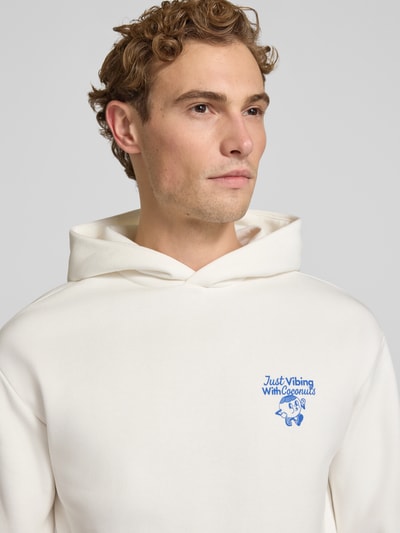 Männermodel trägt Relaxed Fit Hoodie mit Motiv-Print von REVIEW, weiß, Baumwoll-Mix, gerippte Abschlüsse, Nahaufnahme Oberkörper.