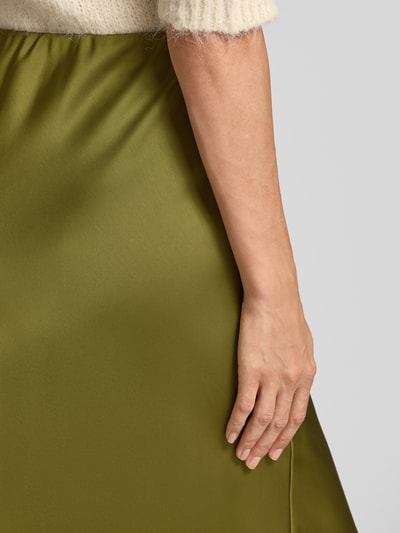 Frauenmodel trägt Midi-Rock aus Satin Modell 'Ve44rona' von ZABAIONE, olivgrün, glatte Textur, Detailaufnahme Nahaufnahme Oberkörper. Damen Midi-Rock von ZABAIONE, Satin, A-Linie, elastischer Bund, Bundweite bei Größe S: 35 cm, Gesamtlänge 95 cm.