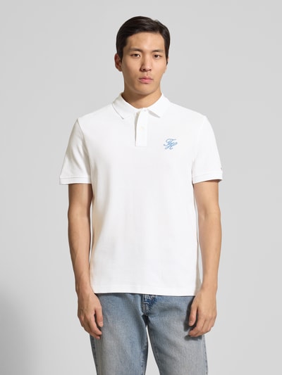 Männermodel trägt Regular Fit Poloshirt aus reiner Baumwolle von Tommy Hilfiger, weiß, unifarben, Logo-Stitching, Ganzkörperansicht von vorne.