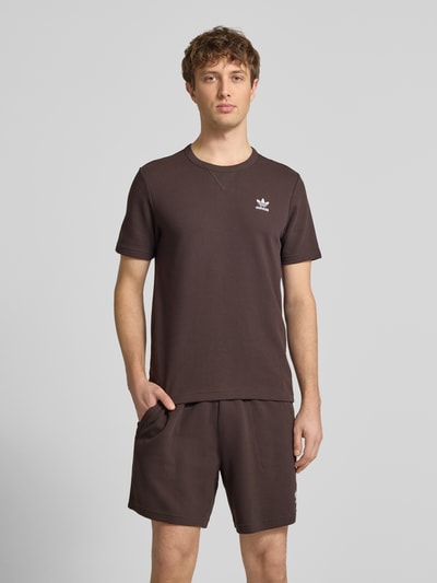Männermodel trägt Regular Fit T-Shirt mit Baumwoll-Anteil Modell 'AUCO' von adidas Originals, Optik: Unifarben, Struktur, Label-Stitching-Applikation, Rundhals, Ärmelform: Kurzarm, Materialverarbeitung: Piqué, Material-Mix, Ganzkörperansicht von vorne.