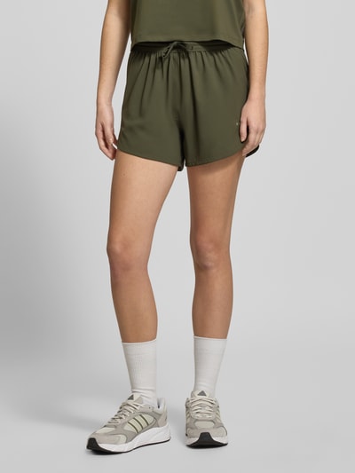 Frauenmodel trägt PUMA x HYROX - Shorts mit Label-Print in Oliv, lockerer Schnitt, elastischer Bund mit Tunnelzug, Nahaufnahme Oberschenkel.