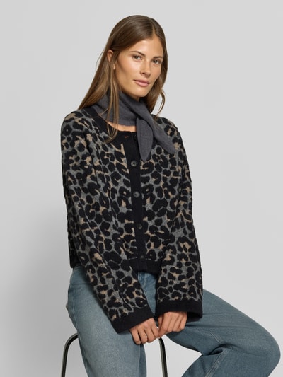 Frauenmodel trägt Regular Fit Cardigan mit Allover-Animal-Print von MYON in Strick-Optik, dunkle Knöpfe, Jeans, Nahaufnahme Oberkörper.