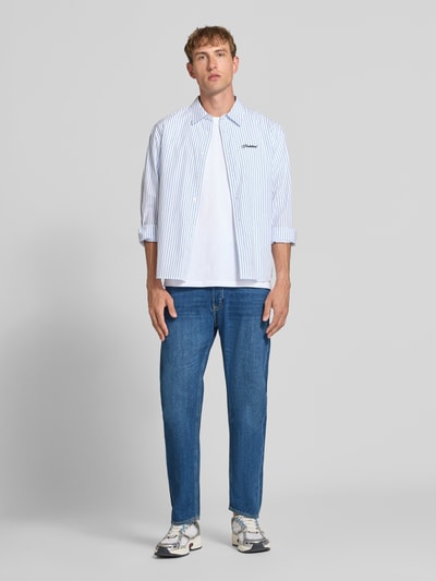Męski model nosi Straight Fit Jeans aus Baumwoll-Mix Modell 'CHRIS' von JACK & JONES, mieszanka bawełny, 5 kieszeni, zapięcie na guzik i zamek błyskawiczny, niebieski odcień, widok całej sylwetki z przodu, szerokość w rozmiarze 32/32: 41 cm, długość wewnętrzna nogawki: 72 cm.