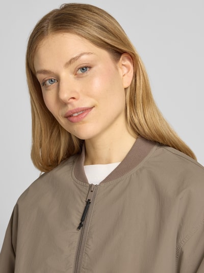 Frauenmodel trägt Jacke mit Pattentaschen Modell 'FACEE' von khujo in Beige mit Stehkragen, Nahaufnahme Oberkörper, Regular Fit.