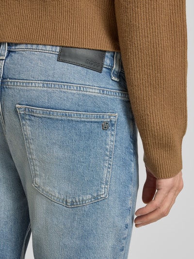 Männermodel trägt Slim Fit Jeans aus Baumwoll-Mix Modell 'DELAWARE BO' von BOSS Orange in hellblauer Denim-Optik, Label-Patch, Label-Stitchings, Label-Prägung, Logo-Applikation, 5-Pocket-Design; Detailaufnahme Rückansicht.