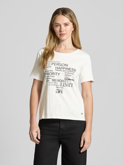 Frauenmodel trägt T-Shirt mit Statement-Print und Ziersteinbesatz von monari in Weiß, Regular-Fit, Reine Baumwolle, Rundhalsausschnitt, Rückenlänge 60 cm bei Größe 36, Vorderansicht Oberkörper.