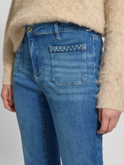 Frauenmodel trägt Flared Fit Jeans mit Flecht-Detail Modell 'Mary' von BRAX aus elastischem Baumwoll-Mix, aufgesetzte Taschen, Nahaufnahme Oberkörper.