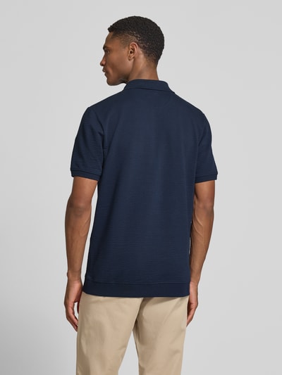 Männermodel trägt Regular Fit Poloshirt aus Baumwoll-Mix von s.Oliver RED LABEL, unifarben dunkelblau, Seersucker-Struktur, Ganzkörperansicht Rückansicht