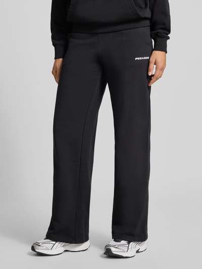 Kobiece modelka ma na sobie spodnie dresowe Wide Fit Sweatpants aus Baumwoll-Mix Model 'ANNI' von PEGADOR, czarny, prosty krój, detal z logo, elastyczny pas, długość wewnętrzna nogawki w rozmiarze S: 78 cm, mieszanka bawełny, Ganzkörperansicht z przodu