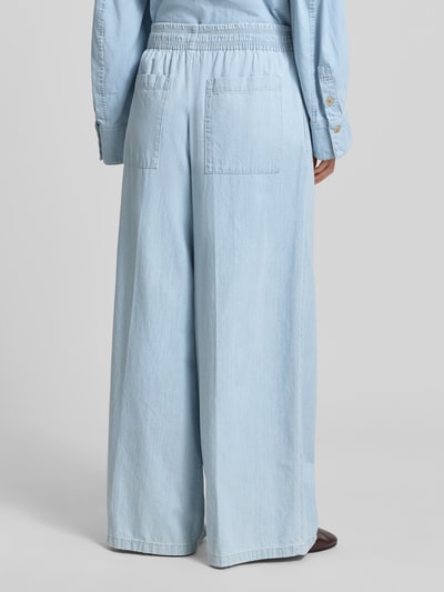 Modelka kobieca nosi Wide Fit Stoffhose in Denim-Optik Modell 'Ceiling' od Drykorn, jasnoniebieska bawełna, elastyczny pas, szerokość w rozmiarze 27/34: 36 cm, długość nogawki wewnętrznej: 79 cm, widok całej sylwetki z tyłu.