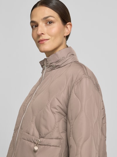 Kobiece model prezentuje Steppjacke mit Kapuze od White Label w kolorze beżowym, prosty krój, tunel w kapturze i pasie, zamek błyskawiczny dwustronny, długość tyłu w rozmiarze 36: 58 cm, szerokość ramion w rozmiarze 36: 51 cm, szerokość w klatce piersiowej w rozmiarze 36: 55 cm, długość rękawów w rozmiarze 36: 58 cm, tekstura matowa, zbliżenie na górną część ciała, widok z przodu