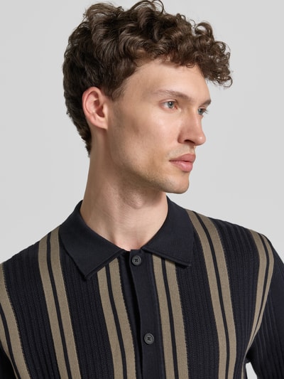 Männermodel trägt Regular Fit Poloshirt aus reiner Baumwolle Marc O'Polo × DFB Travel Collection, Optik:Allover-Muster, gestreift, Nahaufnahme Oberkörper.