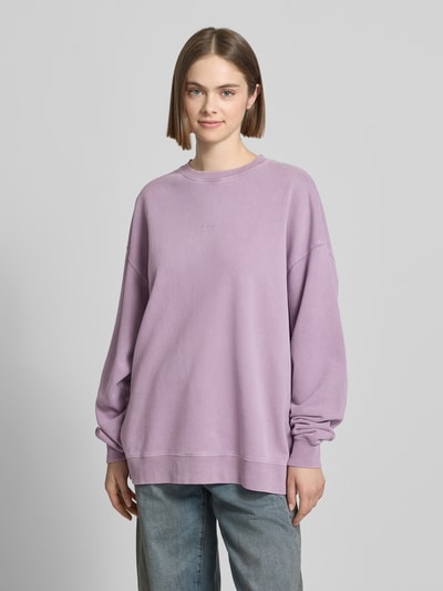 Frauenmodel trägt Oversized Sweatshirt mit Logo-Stitching Modell 'Farmers Market' von OH APRIL aus Reine Baumwolle, Oversized-Fit, Gerippter Rundhalsausschnitt, überschnittene Schultern, Statement-Print auf Rückseite, lavendel, glatte Textur, Ganzkörperansicht von vorne.