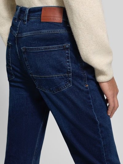 Männermodel trägt Regular Fit Jeans mit Eingrifftaschen von Bugatti aus dunkelblauem Baumwoll-Elasthan-Mix, Detailaufnahme Rückansicht.