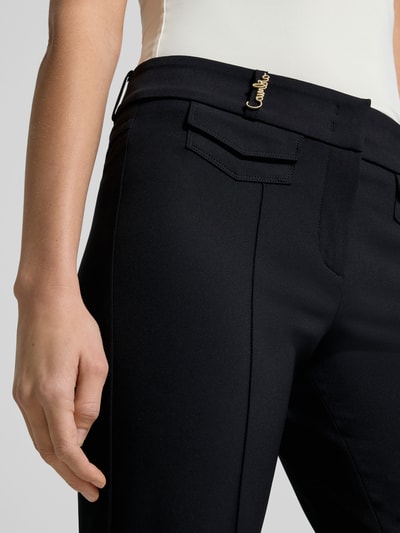 Frauenmodel trägt Bootcut Stoffhose mit Seitentaschen von Cambio, schwarze Hose mit Bügelfalten und Gürtelschlaufen, Nahaufnahme Oberkörper.