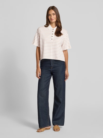 Frauenmodel trägt Poloshirt mit kurzer Knopfleiste von Christian Berg Woman aus Reine Baumwolle, Gerader-Schnitt, Polokragen, 1/2-Arm, beige-weiß gestreift, Rückenlänge 44 cm, Ganzkörperansicht von vorne.