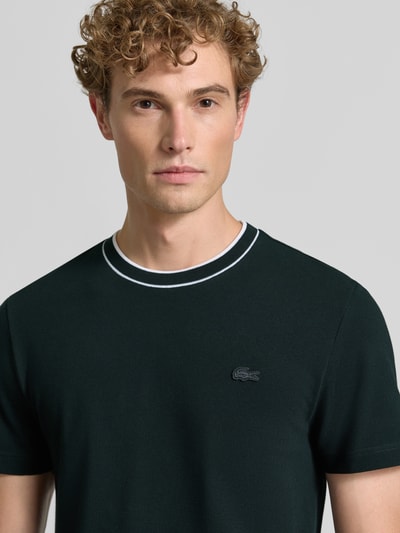 Męski model nosi Regular Fit T-Shirt aus Baumwoll-Mix od Lacoste, ciemny kolor, z subtelną fakturą, Nahaufnahme górnej części ciała.