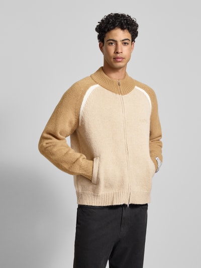 Männermodel trägt Strickjacke mit Reißverschluss von ANOTHER COTTON LAB im Material-Mix mit Rundhalsausschnitt, Eingrifftaschen, Regular-Fit, Beige- und Brauntöne, Gerippte-Abschlüsse, Label-Details, Ganzkörperansicht von vorne.