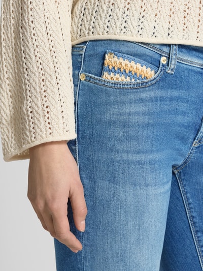 Frauenmodel trägt Slim Fit Jeans aus Baumwoll-Mix in verkürzter Passform von Cambio, helle Waschung, Kontrastnähte, Nahaufnahme Oberkörper.