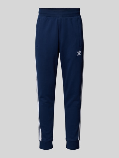 Produktfoto, Sweatpants mit elastischem Bund von adidas Originals aus Baumwoll-Mix in Dunkelblau mit weißen Streifen, Lockerer-Schnitt, Eingrifftaschen, Label-Stitching, Innenbeinlänge 38 cm bei Größe M.