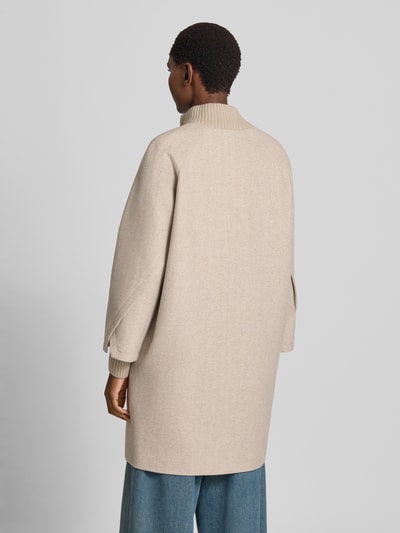 Frauenmodel trägt Mantel aus Woll-Mix mit gestricktem Stehkragen von COMMA in Beige, sichtbare Struktur, lockerer Schnitt, Ganzkörperansicht Rückansicht. Straight Fit, seitliche Eingrifftaschen, Druckknopfverschluss, gestrickte Ärmelabschlüsse, Teil mit Viskose-Anteil.