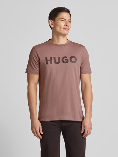 Männermodel trägt Regular Fit T-Shirt aus reiner Baumwolle Modell 'DULIVIO' von HUGO in Optik: Unifarben mit Label-Print, Ganzkörperansicht von vorne.