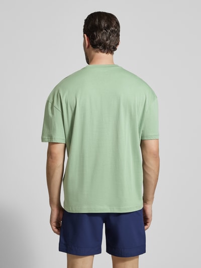 Männermodel trägt T-Shirt mit Logo und Rundhalsausschnitt von EA7 Emporio Armani, Reine Baumwolle, Regular-Fit, Rückenlänge 68 cm, Ganzkörperansicht Rückansicht.