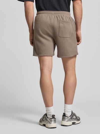 Männermodel trägt Regular Fit Shorts aus Baumwoll-Mix von Tommy Jeans, unifarben, elastischer Bund mit Tunnelzug, Sweat-Material, Ganzkörperansicht Rückansicht.